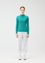 A woman faces forward against a white background, wearing the CROSSING KNIT teal ribbed sweater from PLEATS PLEASE ISSEY MIYAKE, paired with light gray plaid pants and white sneakers.
