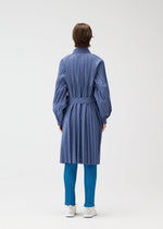 A person faces away, wearing the SMOOTH COAT by PLEATS PLEASE ISSEY MIYAKE in blue with a belt, paired with bright blue pleated tights and white shoes against a plain light background.