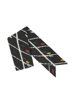 The CROSSING DOTS SCARF by PLEATS PLEASE ISSEY MIYAKE features black fabric with diagonal white stripes and red, yellow, and green dots—ideal for pairing with a suit or adding flair to your outfit. - BLACK （no.15）