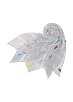 The CROSSING DOTS SCARF by PLEATS PLEASE ISSEY MIYAKE is a pleated light gray accessory with abstract city-inspired patterns, displayed in a spiral with pointed ends fanned out like petals against a white background.