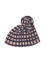 The BASKET MADAME-T by PLEATS PLEASE ISSEY MIYAKE is a pleated stole featuring a navy blue and beige block check print, displayed spiraled on a white backdrop.