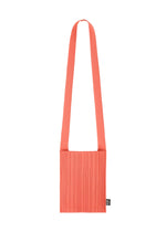 The CREPE KNIT BAG by PLEATS PLEASE ISSEY MIYAKE is a coral pink pleated bag with a wide strap and a small black tag on the side, shown against a plain white background. - LIGHT PINK （no.20）