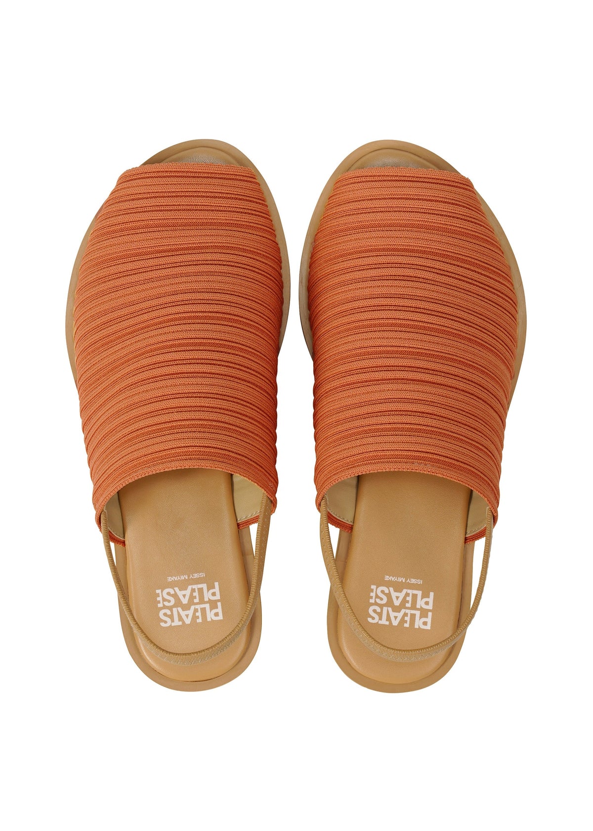 A pair of orange PLEATS KNIT SANDALS by PLEATS PLEASE ISSEY MIYAKE, slip-on style with ribbed knit uppers, subtle pleat lines, and tan soles. The insoles display “PLEASE PLEASE” in white text. View from above. view 6 of 10