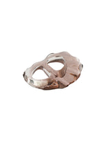 The SHELL SCARF RING by PLEATS PLEASE ISSEY MIYAKE is an abstract, clear glass accessory with two oval cutouts and wavy edges, evoking a modern seashell shape against a white background.