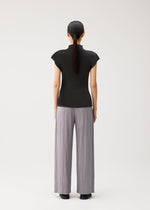 A person with long dark hair in a ponytail stands facing away, wearing the MIST AUGUST black lightweight short-sleeve top and wide, light gray pleated pants by PLEATS PLEASE ISSEY MIYAKE against a plain white background.