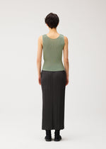 A person with short dark hair, seen from behind, is wearing the MIST SEPTEMBER lightweight green round-neck tank top and a long black pleated skirt by PLEATS PLEASE ISSEY MIYAKE, paired with black shoes, against a plain white background.
