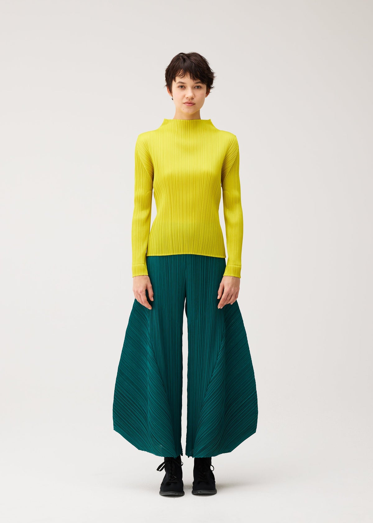 A person models the MONTHLY COLORS : OCTOBER by PLEATS PLEASE ISSEY MIYAKE—bright yellow ribbed turtleneck and color block pants—standing against a plain white background with a neutral expression. view 8 of 11