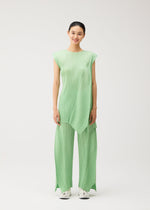 A woman stands smiling in the FOLD sleeveless, light green pleated top with matching wide-leg, flared pants featuring pockets by PLEATS PLEASE ISSEY MIYAKE, paired with white sneakers against a plain white background.