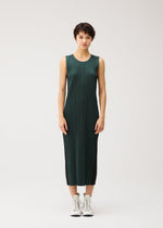 A person with short dark hair wears the COTTON DENIM by PLEATS PLEASE ISSEY MIYAKE, a sleeveless dark green ribbed dress, paired with white lace-up boots against a plain light background.