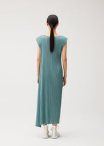 A woman with straight black hair in a low ponytail wears the FOLD sleeveless teal pleated maxi dress with a round neckline from PLEATS PLEASE ISSEY MIYAKE, paired with white sneakers, standing against a plain light background and facing away from the camera.