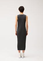 A person with short hair faces away, wearing the PLEATS PLEASE ISSEY MIYAKE COTTON DENIM BLACK sleeveless midi dress and white high-top sneakers against a plain light background.