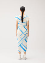 A woman stands with her back to the viewer, wearing the FOLD LINE midi dress by PLEATS PLEASE ISSEY MIYAKE—a white dress featuring blue geometric stripes and French sleeves. She pairs it with white socks and white sneakers, and her straight dark hair is tied in a low ponytail. The plain, light-colored background highlights the minimalist design of her ensemble.