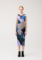 A woman stands against a plain background, wearing the “SURPRISE!” sleeveless, round-neck dress by PLEATS PLEASE ISSEY MIYAKE, featuring an abstract print in purple, green, black, and tan, paired with black lace-up shoes.