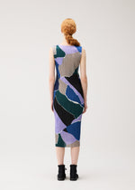 A person with long red hair in a low braid is seen from behind, wearing the SURPRISE! dress by PLEATS PLEASE ISSEY MIYAKE—a sleeveless, knee-length piece featuring an abstract pattern in blue, green, tan, and black—paired with black ankle boots, standing against a plain white background.