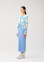 A woman stands in the FOLD LINE dress by PLEATS PLEASE ISSEY MIYAKE, showcasing its minimalist pleated light blue design, styled with a white and blue patterned cardigan and white high-top sneakers against a plain light background.