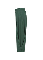 The PLEATS PLEASE ISSEY MIYAKE A-POC BOTTOMS are wide-leg dark green pleated pants with an elastic waistband, showcasing A-POC structure and overlapping fabric panels that wrap around the front and fasten at the ankle for a flared yet tapered silhouette, shown against a plain white background.