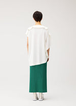 A person with short dark hair faces away, wearing the PLEATS PLEASE ISSEY MIYAKE A-POC SLICE loose round-neck tunic with an asymmetrical hem, a long green pleated skirt, and white shoes against a plain light background.