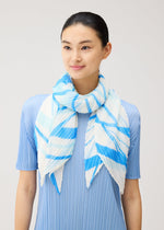A woman with dark hair pulled back wears a light blue, pleated, short-sleeved top and drapes the PLEATS PLEASE ISSEY MIYAKE FOLD LINE SCARF—a matching blue and white striped, pleated scarf—loosely around her neck, its delicate folds reminiscent of a folding screen, set against a plain light gray background.