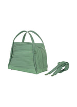The BIAS PLEATS BAG by PLEATS PLEASE ISSEY MIYAKE is shown in light green with textured, diagonal pleating, two handles, and a detachable matching strap placed beside it on a white background.
