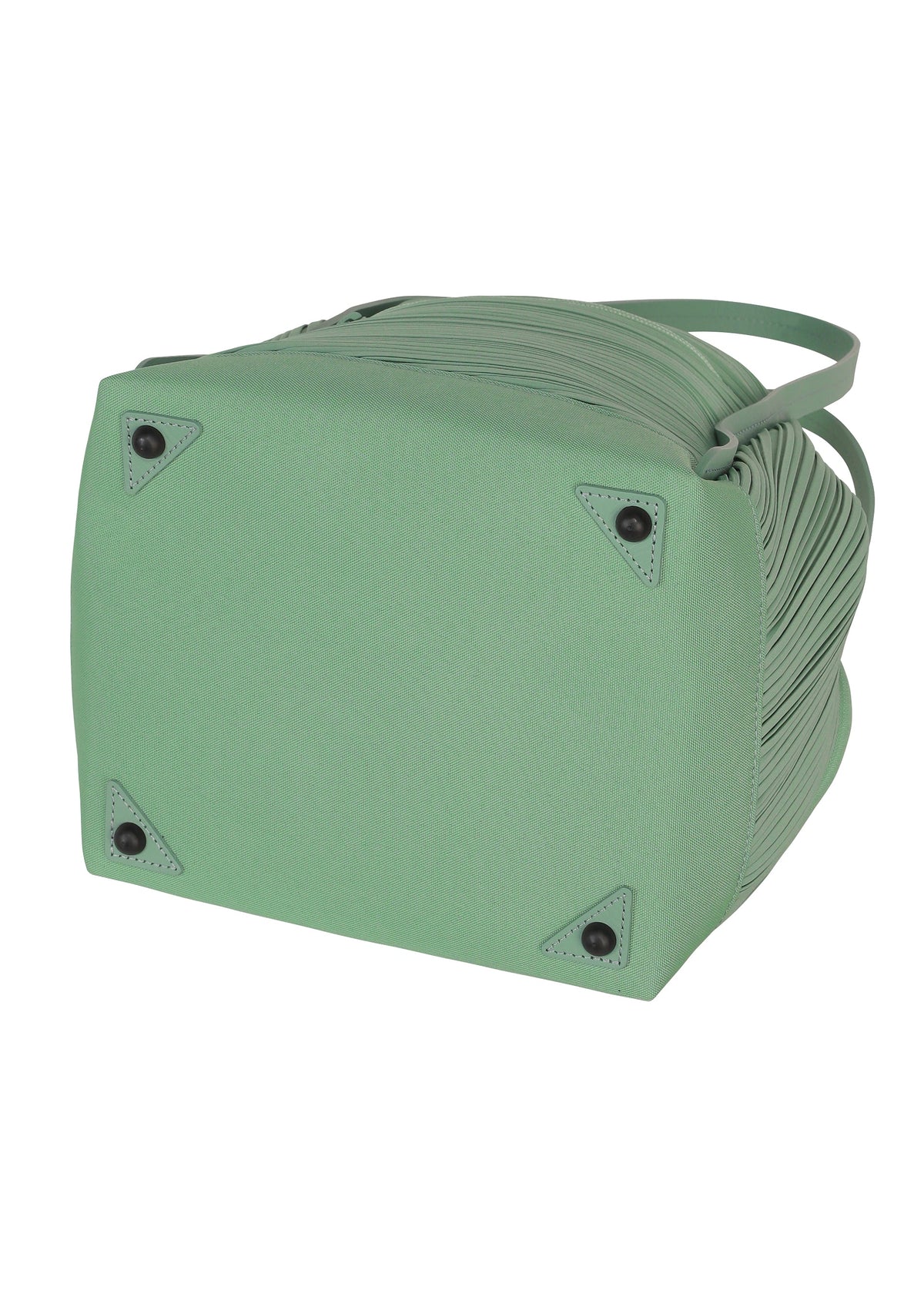 The image shows the bottom view of the BIAS PLEATS BAG by PLEATS PLEASE ISSEY MIYAKE in light green, featuring four black protective studs at each corner and a structured, textured body. view 6 of 9
