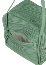 A close-up of the BIAS PLEATS BAG by PLEATS PLEASE ISSEY MIYAKE in light green shows its partially open zipper revealing a beige interior pocket. This compact bag features two handles and textured, wavy pleated detailing on the surface.