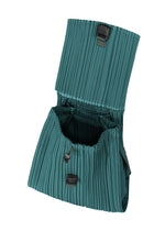 The PLEATS KNAPSACK by PLEATS PLEASE ISSEY MIYAKE features teal pleated fabric, a flap opening with two black buckles, and an expandable accordion-style design shown against a white background.