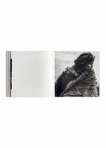 An open copy of ISSEY MIYAKE (Limited Collectors Edition) by ISSEY MIYAKE BOOKS reveals a blank left page and, on the right, a black-and-white photograph of a person draped in a textured blanket, gazing to the right—a striking image that captures Issey Miyake’s design philosophy.